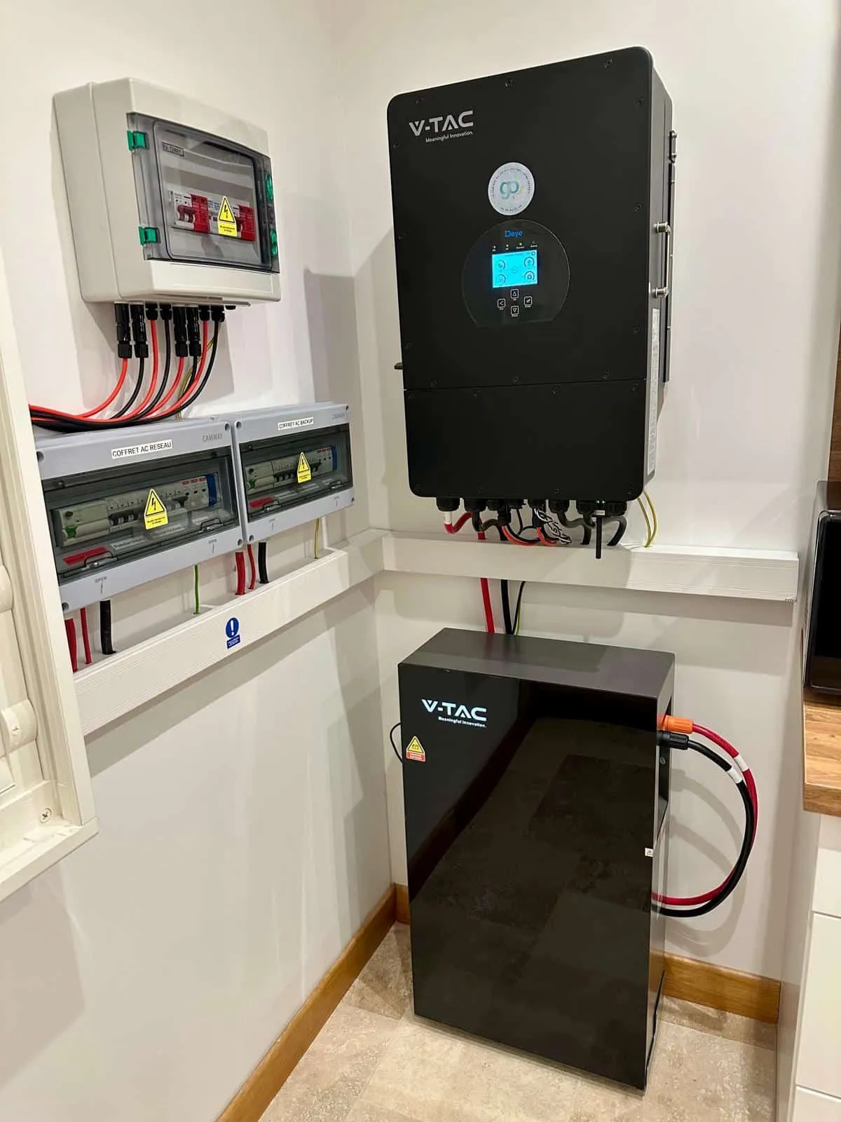 Onduleur hybride noir et batterie installés au mur du local technique