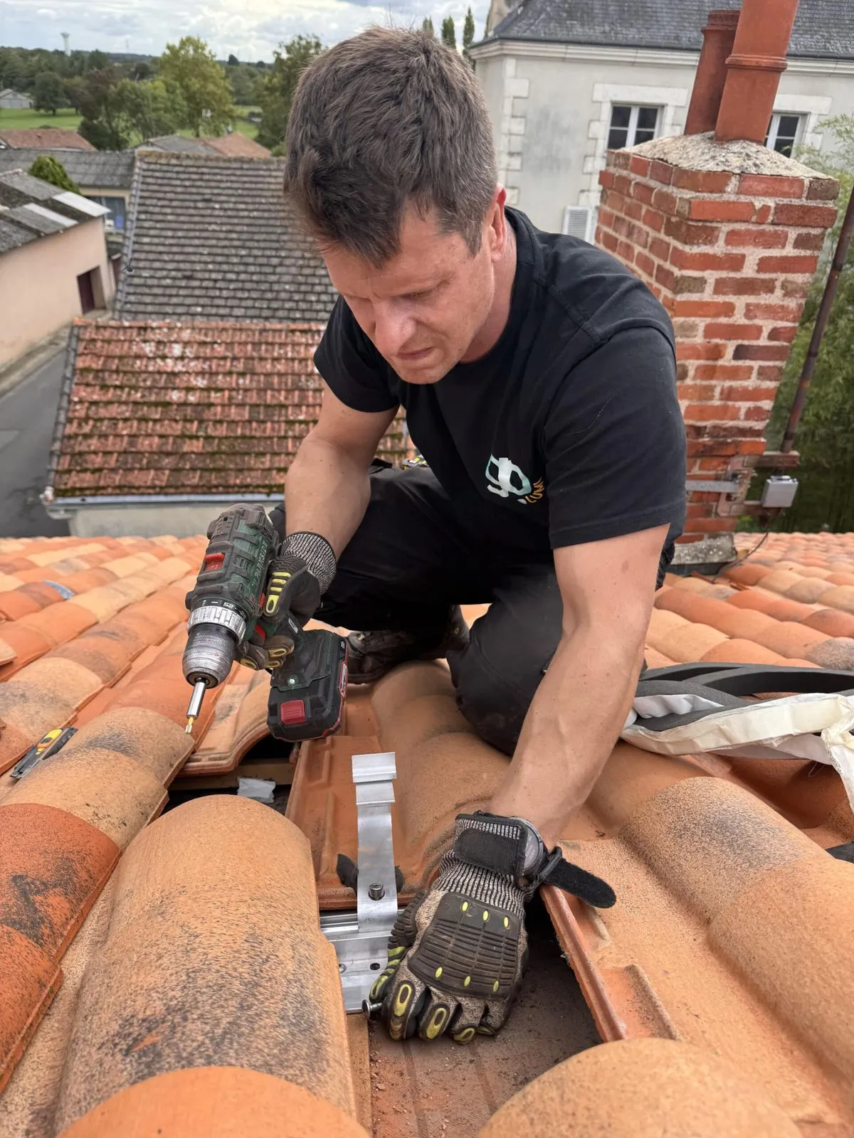 Technicien GoLumi vissant un crochet de fixation sous les tuiles